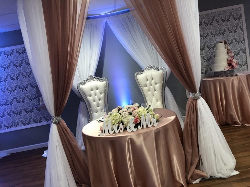 small round table with mr and mrs signs on brown tablecloth with large white chairs